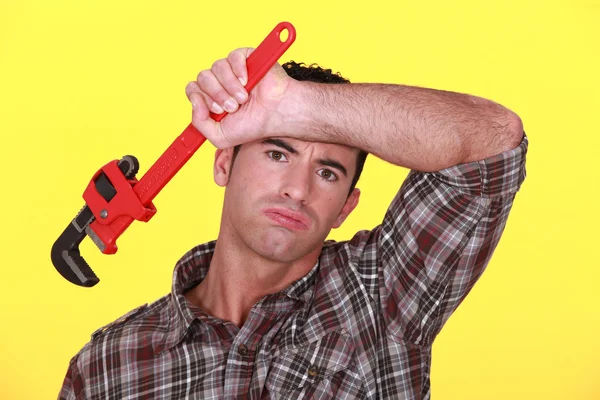 Exhausted craftsman with adjustable spanner against yellow background — Stock Photo, Image