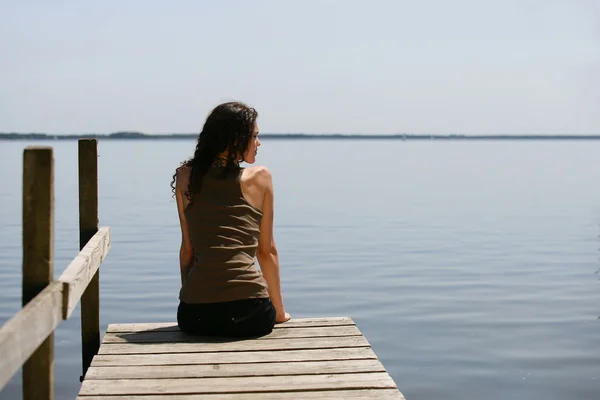 Femme assise sur un ponton — Photo