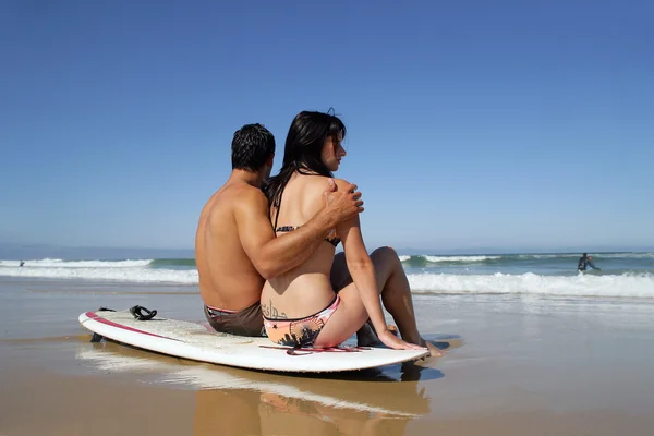 Couple sat on a surfboard — Zdjęcie stockowe