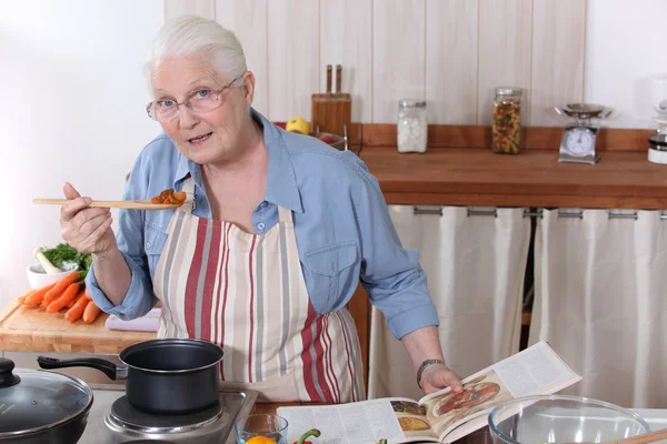 Mulher idosa cozinhar jantar com a ajuda de uma receita — Fotografia de Stock