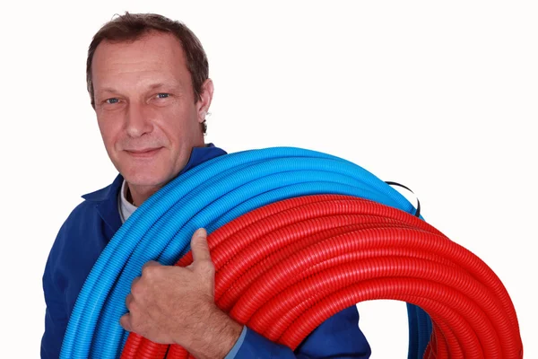 Plumber with reels of red and blue tubing — Stock Photo, Image