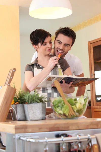 Junges Paar in einer Küche mit einem Kochbuch — Stockfoto