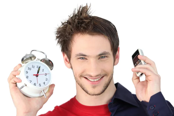 Man holding alarm clock and mobile telephone — Stock Photo, Image