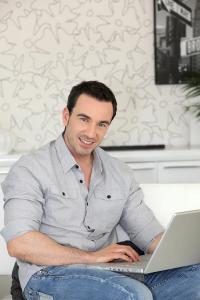 Sonriente hombre con portátil en el interior — Foto de Stock