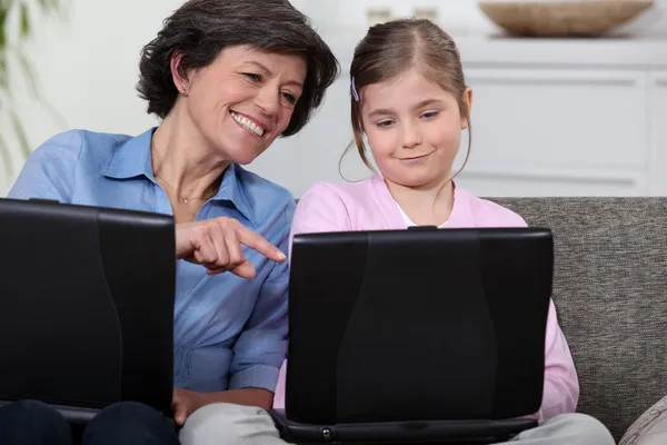 Mãe e filha filho no sofá com seus próprios laptops — Fotografia de Stock