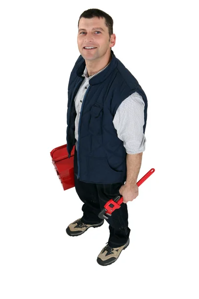 Tradesman segurando uma chave de tubo e uma caixa de ferramentas — Fotografia de Stock