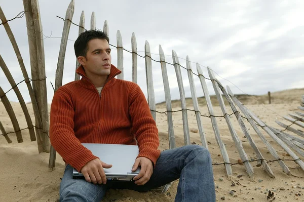 Человек сидел на пляже со своим компьютером — стоковое фото