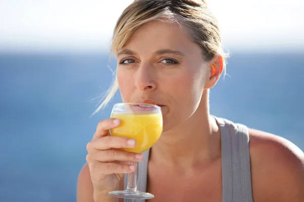 Μια γυναίκα πίνει ένα ποτήρι χυμό πορτοκάλι. — Φωτογραφία Αρχείου