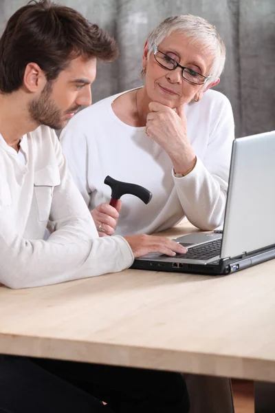 Homem ajudando uma senhora idosa com seu laptop — Fotografia de Stock