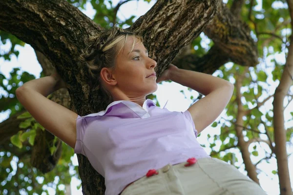 Kvinnan lutar sig mot ett träd — Stockfoto