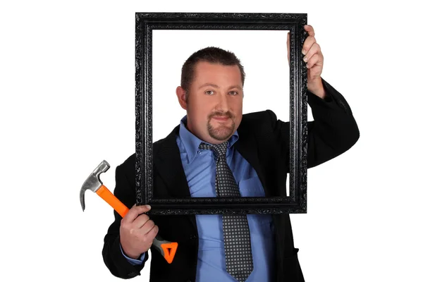 Man in a suit with a picture frame and hammer Royalty Free Stock Photos