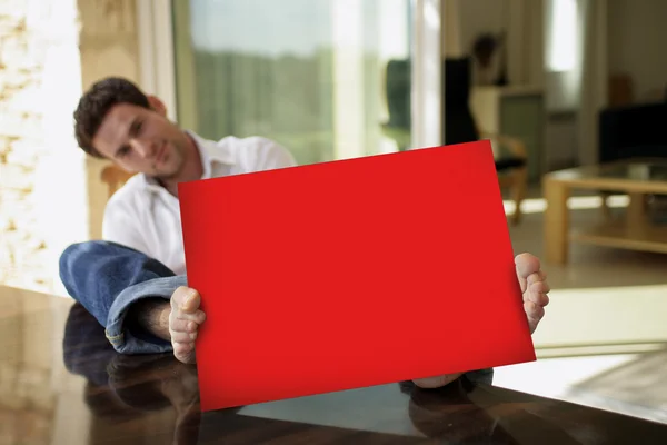 Άνθρωπος που καθόταν στο αίθριο του με κόκκινο αφίσα — Φωτογραφία Αρχείου