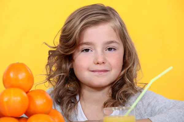 Νεαρό κορίτσι με πορτοκάλια και ένα ποτήρι χυμό — Φωτογραφία Αρχείου