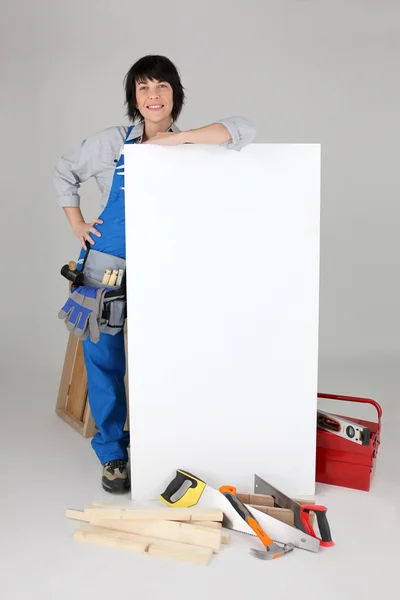 Carpintero femenino con una tabla en blanco para su mensaje —  Fotos de Stock