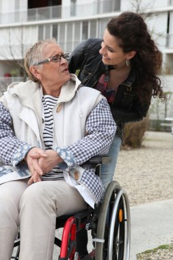 Young woman helping a senior in a wheelchair clipart