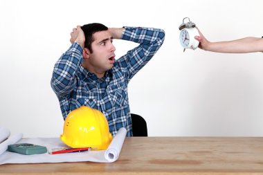 Shocked worker watching alarm clock clipart