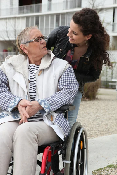 年轻女子帮助一位坐在轮椅上的高级 — 图库照片
