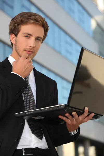 Inteligentny człowiek trzyma laptopa stojący na zewnątrz — Zdjęcie stockowe