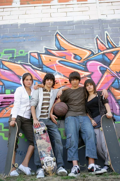 Teenagers posing in front of tagged wall — Stock Photo, Image