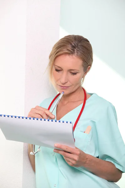 Medic wearing stethoscope examining patient's chart — Stock Photo, Image