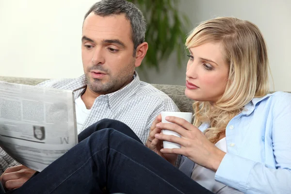 Paar liest Zeitung auf Couch — Stockfoto