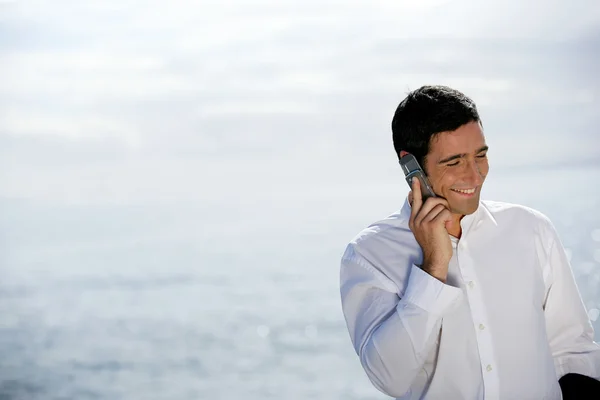 Homme utilisant son téléphone portable au bord de la mer — Photo