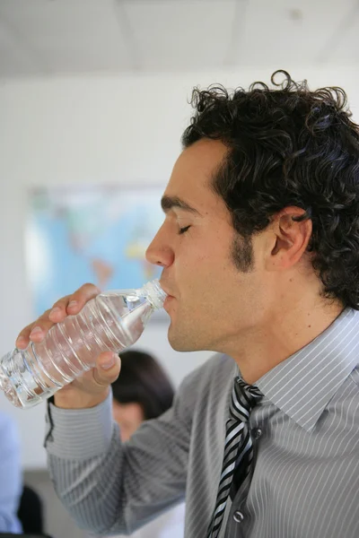 Бизнесмен пьет бутилированную воду — стоковое фото