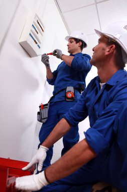 Electricians installing circuit breaker clipart