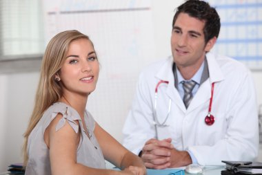 Young female patient consulting with her doctor clipart