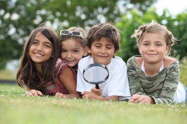 Kids playing with magnifying glass in park clipart