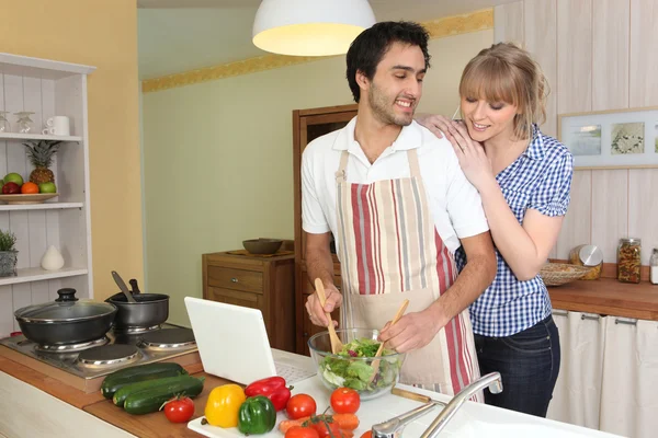 Jovem fazendo uma salada com seu parceiro — Fotografia de Stock