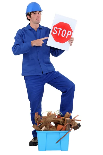 Man stood holding stop sign by crate of refuge — Stock Photo, Image