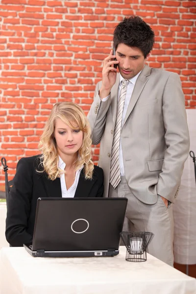 Empresário e assistente assistindo laptop — Fotografia de Stock
