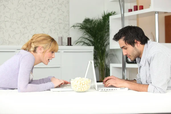 Giovane coppia seduta faccia a faccia con il computer portatile — Foto Stock