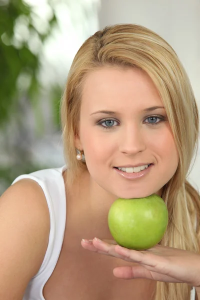 Ξανθιά κοπέλα που ακουμπά το πηγούνι σε πράσινο μήλο — Φωτογραφία Αρχείου