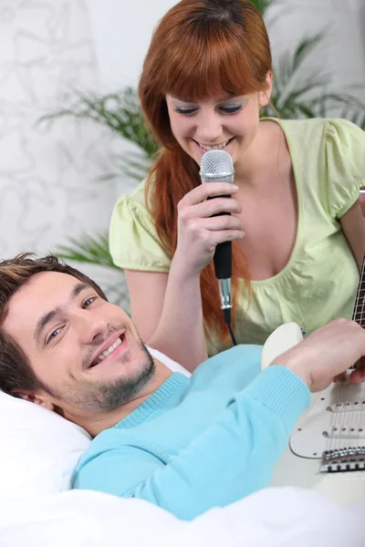 Ein Mann spielt Gitarre und eine Frau singt zu Hause — Stockfoto
