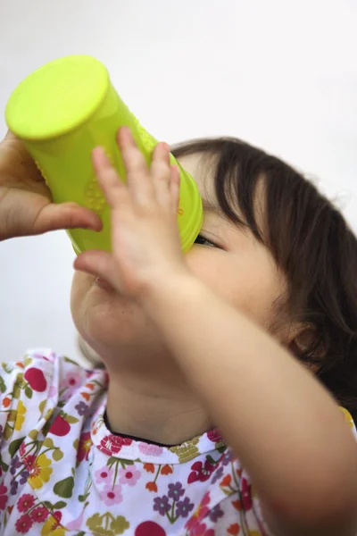 Liten flicka tömma ett glas vatten — Stockfoto