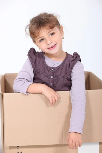 Little girl playing with cardboard box — Stock Photo, Image