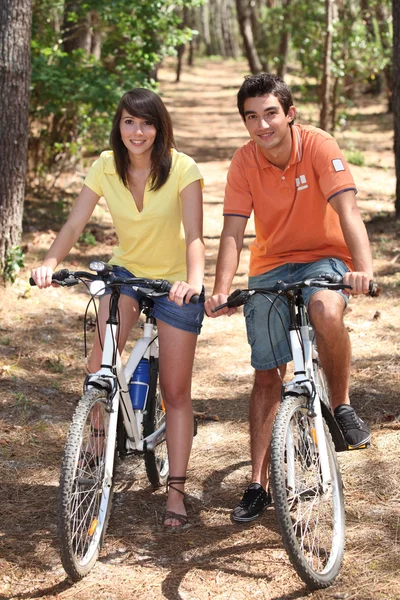 Jovem casal andar de bicicleta em uma floresta — Fotografia de Stock