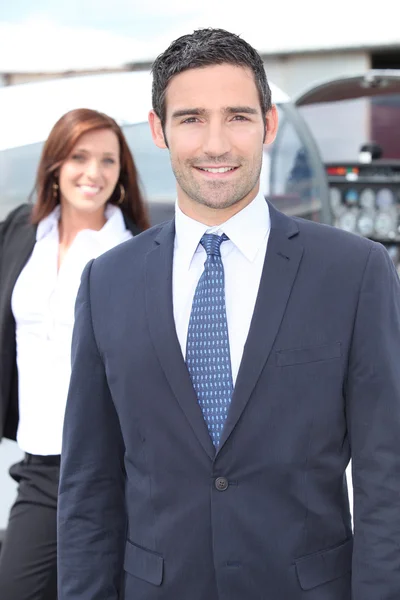 Businessman standing with a woman and light aircraft — Stock Photo, Image