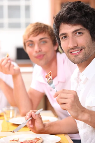 Dva mladí muži jíst jídlo — Stock fotografie