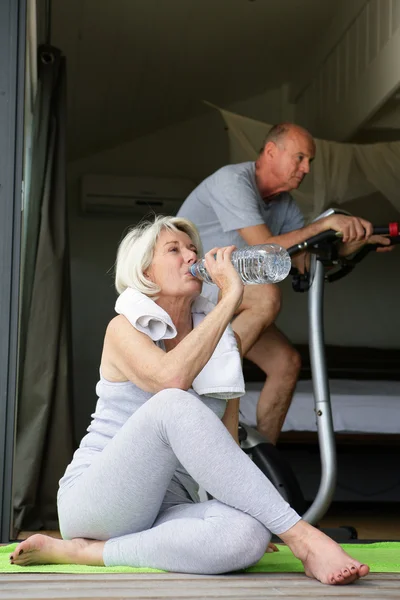 Пара пожилых людей, занимающихся спортом дома — стоковое фото