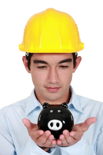 Young construction worker with piggy bank in hands — Stock Photo, Image
