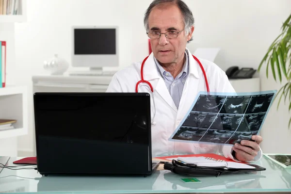 Старший врач проверяет рентген в своем кабинете — стоковое фото