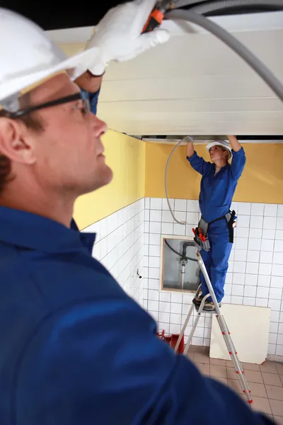 Arbeiter installieren Rohrleitungen in der Decke — Stockfoto