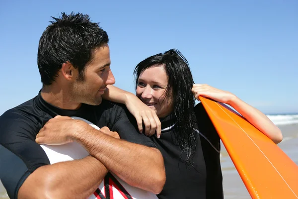 Pareja parada en la playa en trajes de neopreno esperando para surfear —  Fotos de Stock