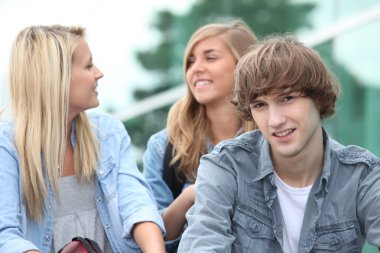 Three students sitting outside on some steps clipart