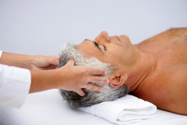 Mature man having a scalp massage clipart