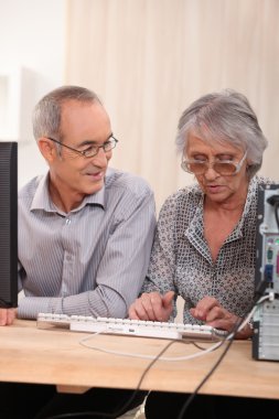 Elderly couple learning computer skills clipart