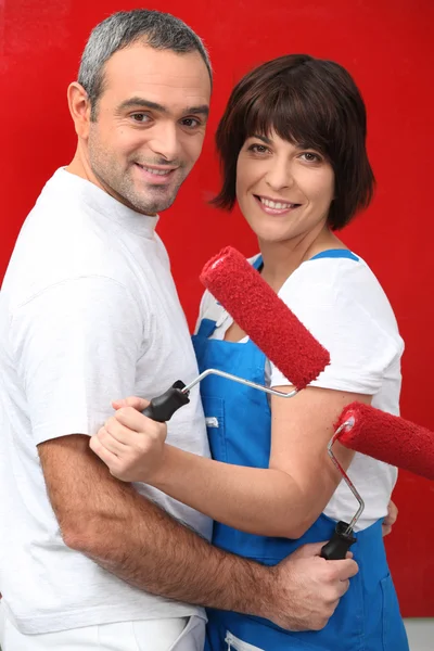 Una pareja pintando su pared de rojo . —  Fotos de Stock